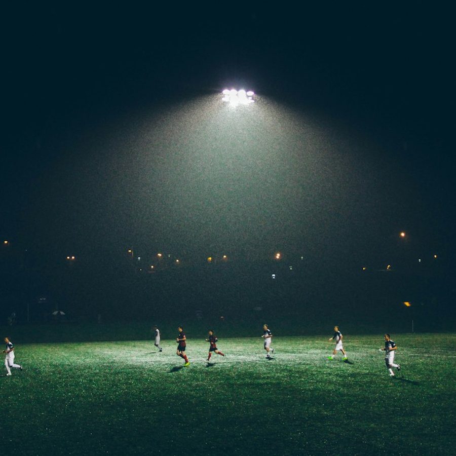 A five a side game under floodlights on a pitch at night.