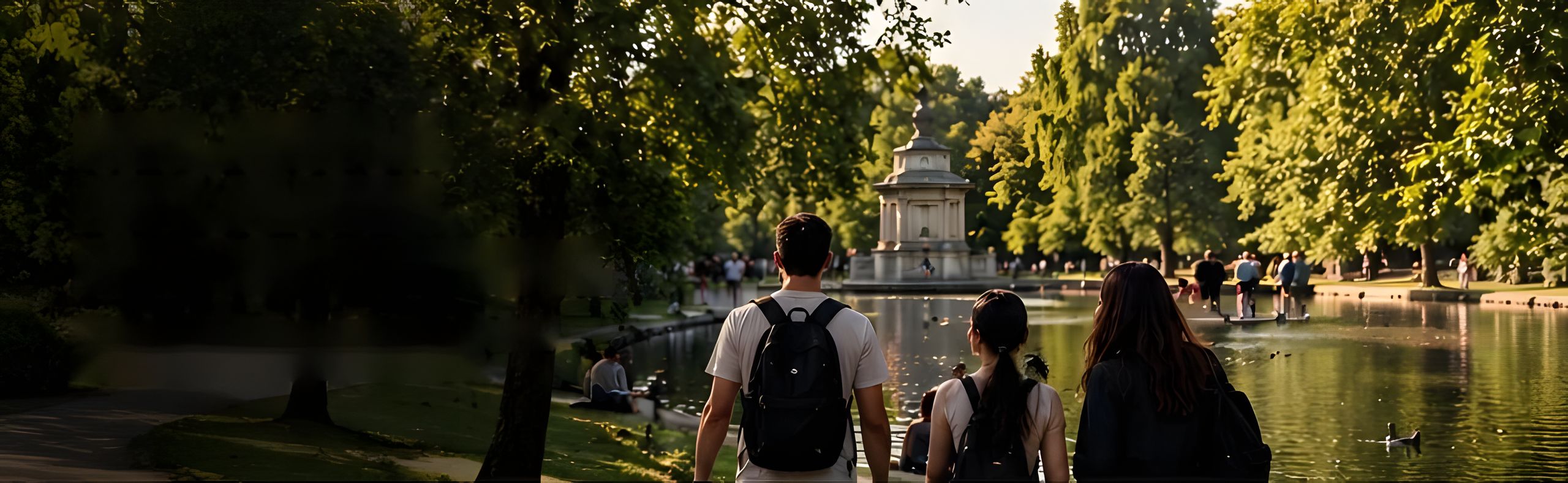 Three friends with backpacks walking beside a lake in a green city park on a summer evening.